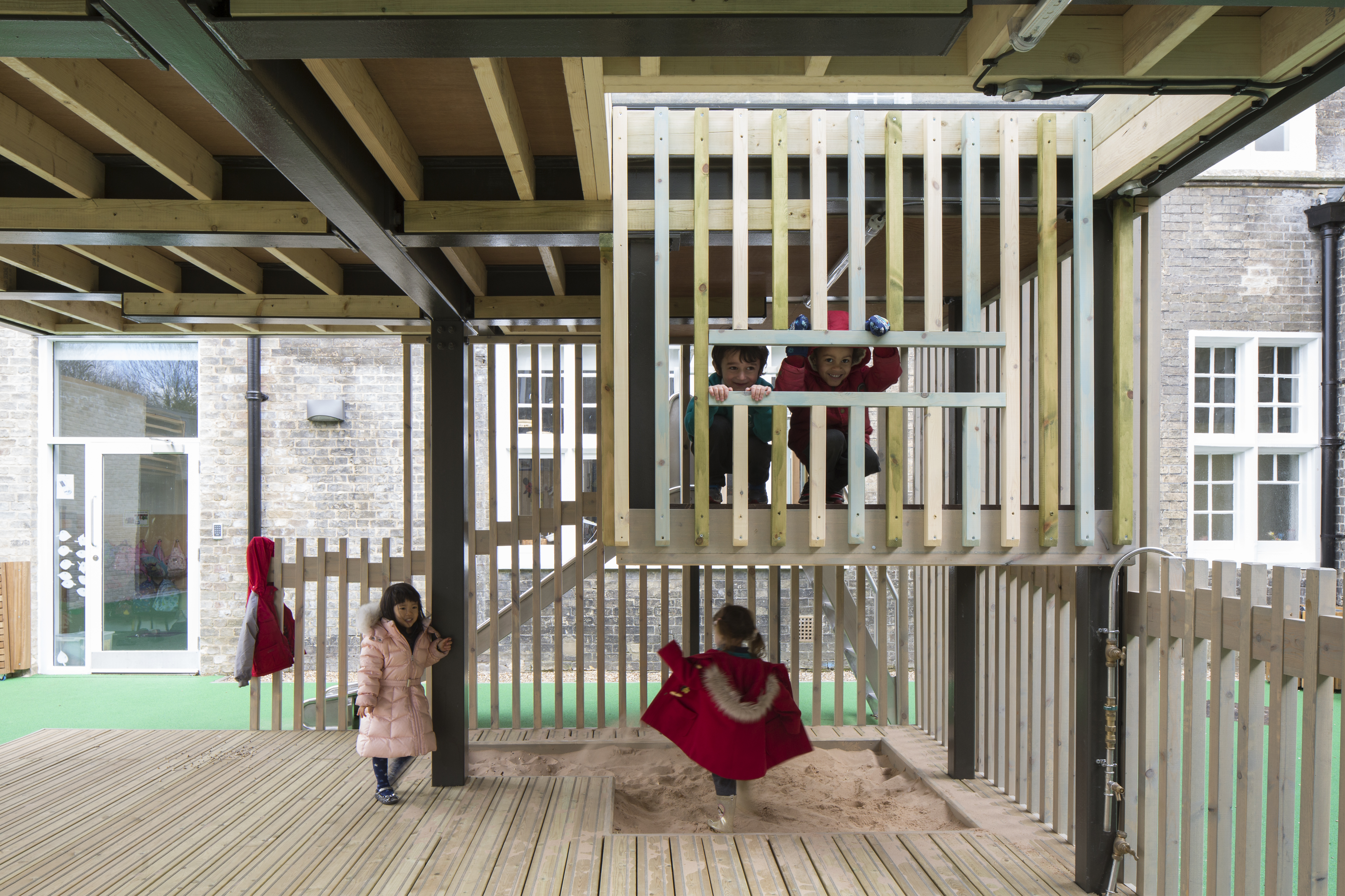 Interior of the outdoor classroom designed by CDC studios, with wooden balustrades, floor, and sandpit.