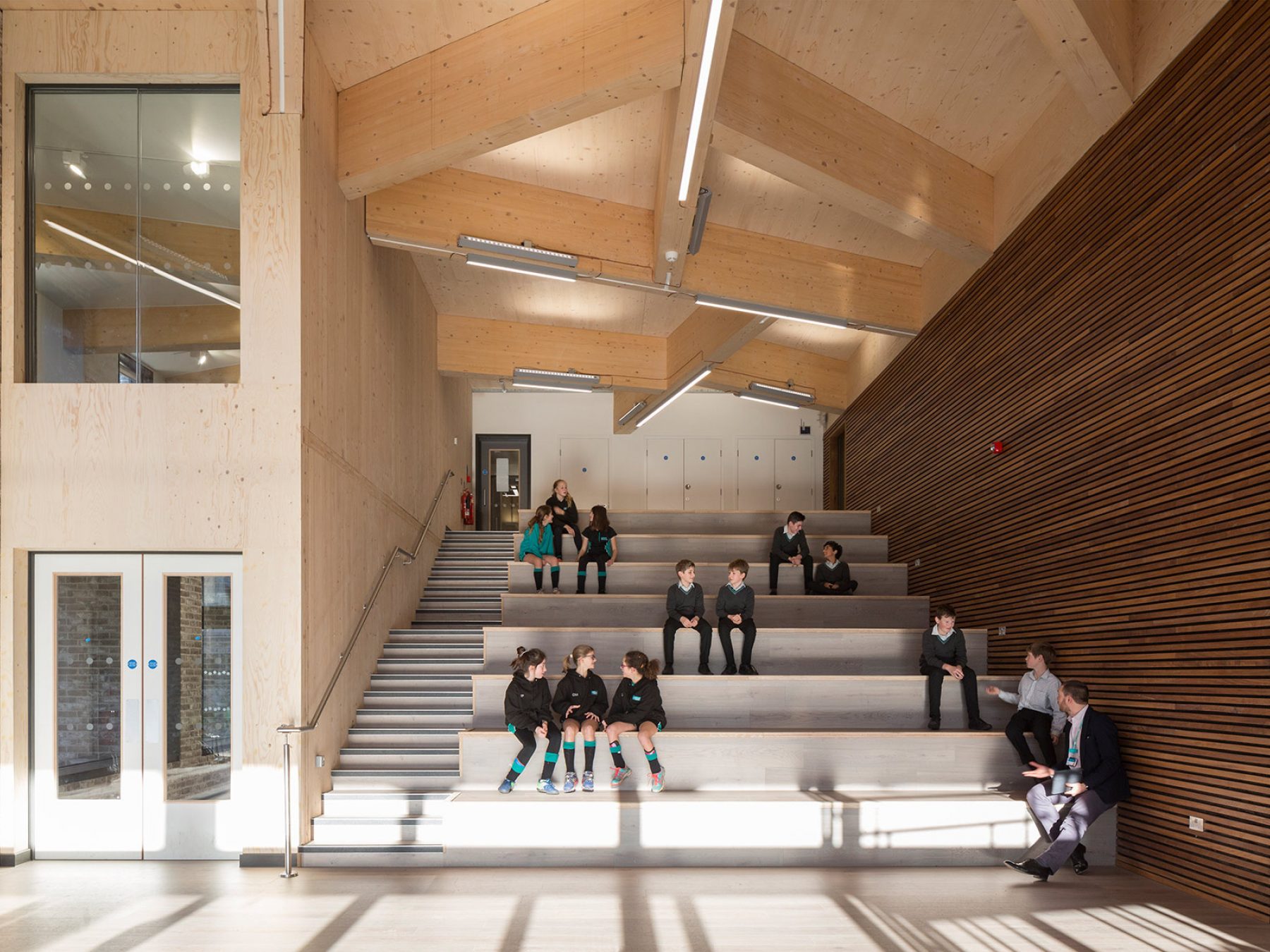 Interior stepped seating with sports learning school | CDC studio cambridge architects, with students conversing.