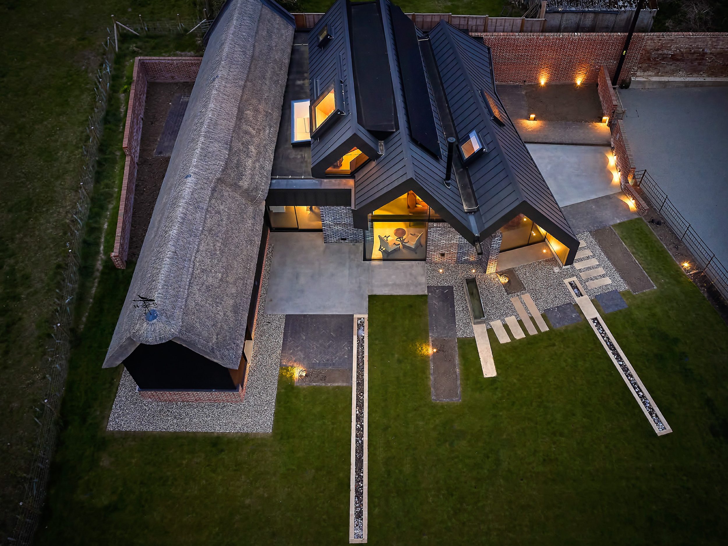 Aerial view of a thatch and zinc gabled house at night | cambridge architects CDC Studio