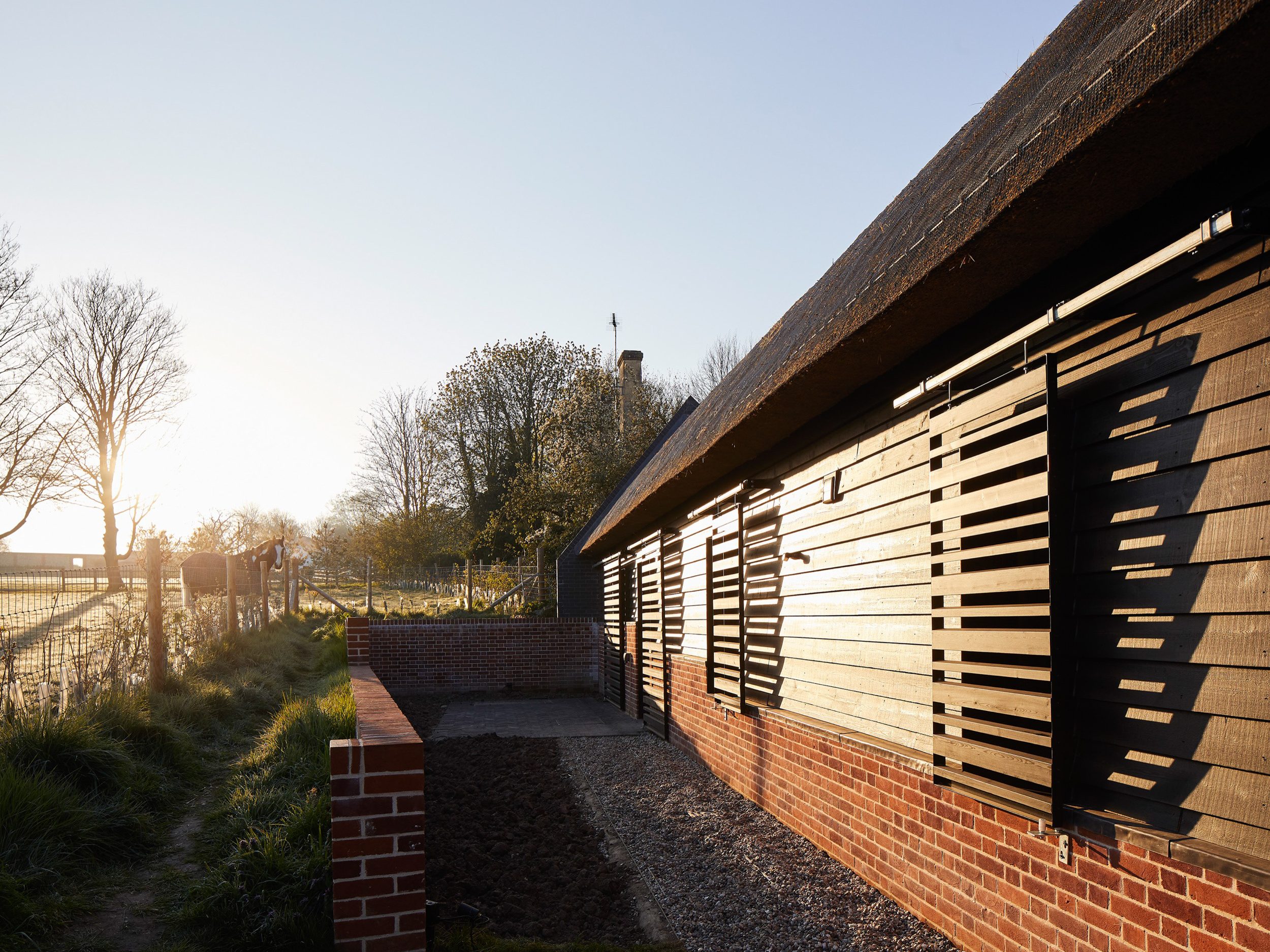 Sunrise highlighting timber shutters of Cambridgeshire barn | cdc studio cambridge architects