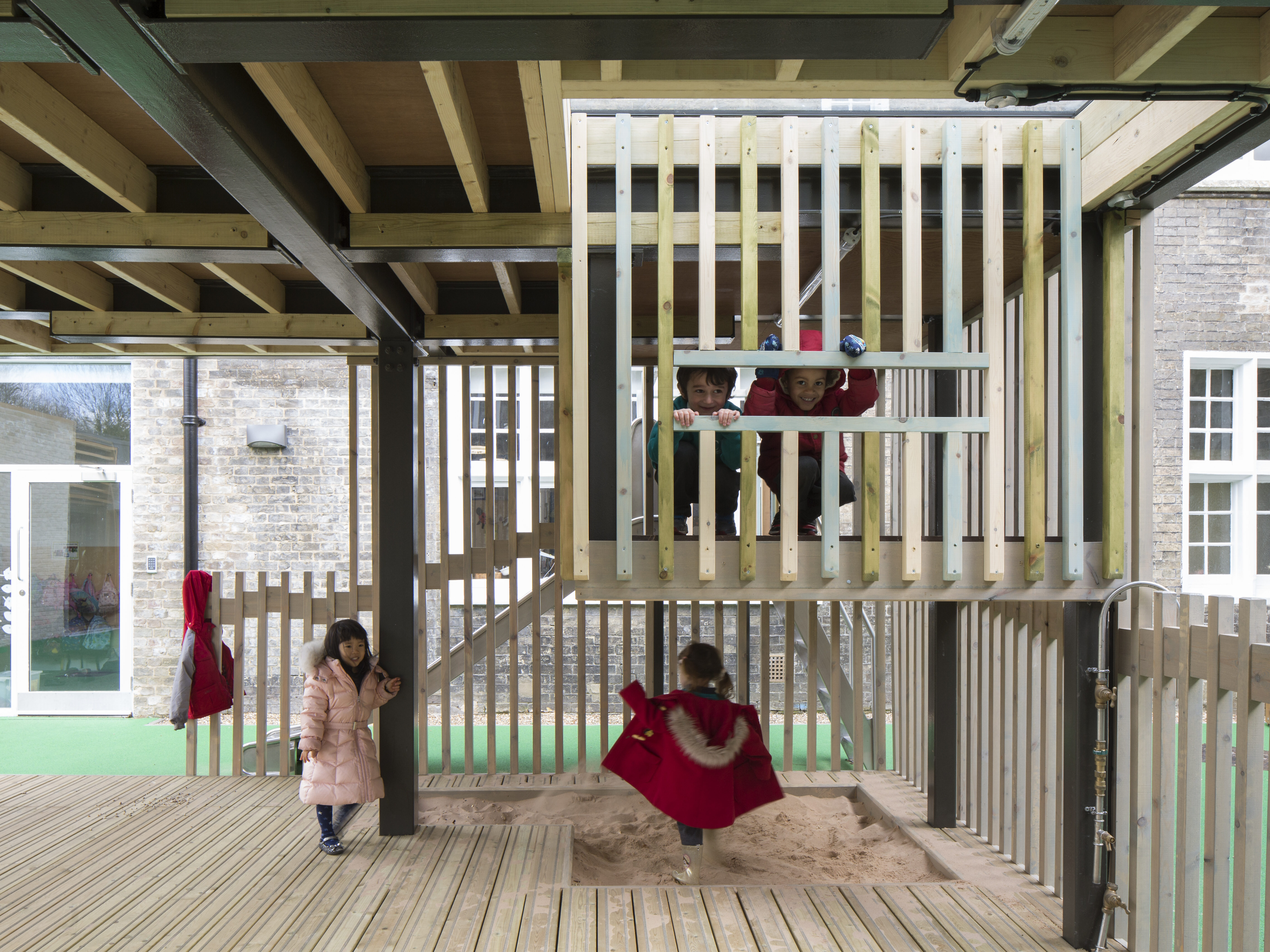 Interior of the outdoor classroom designed by CDC studios, with wooden balustrades, floor, and sandpit.
