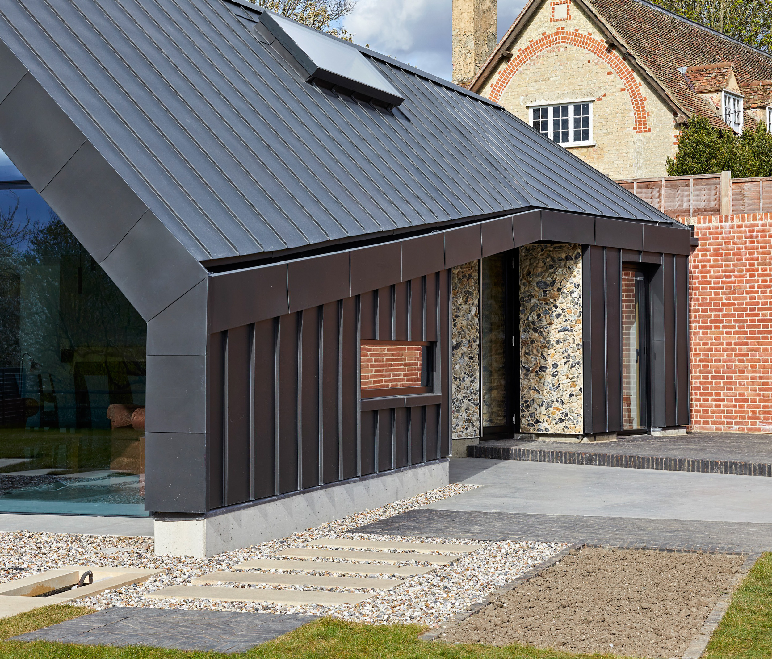 Zinc pitched roof meeting flint wall of house | cdc studio cambridge architects