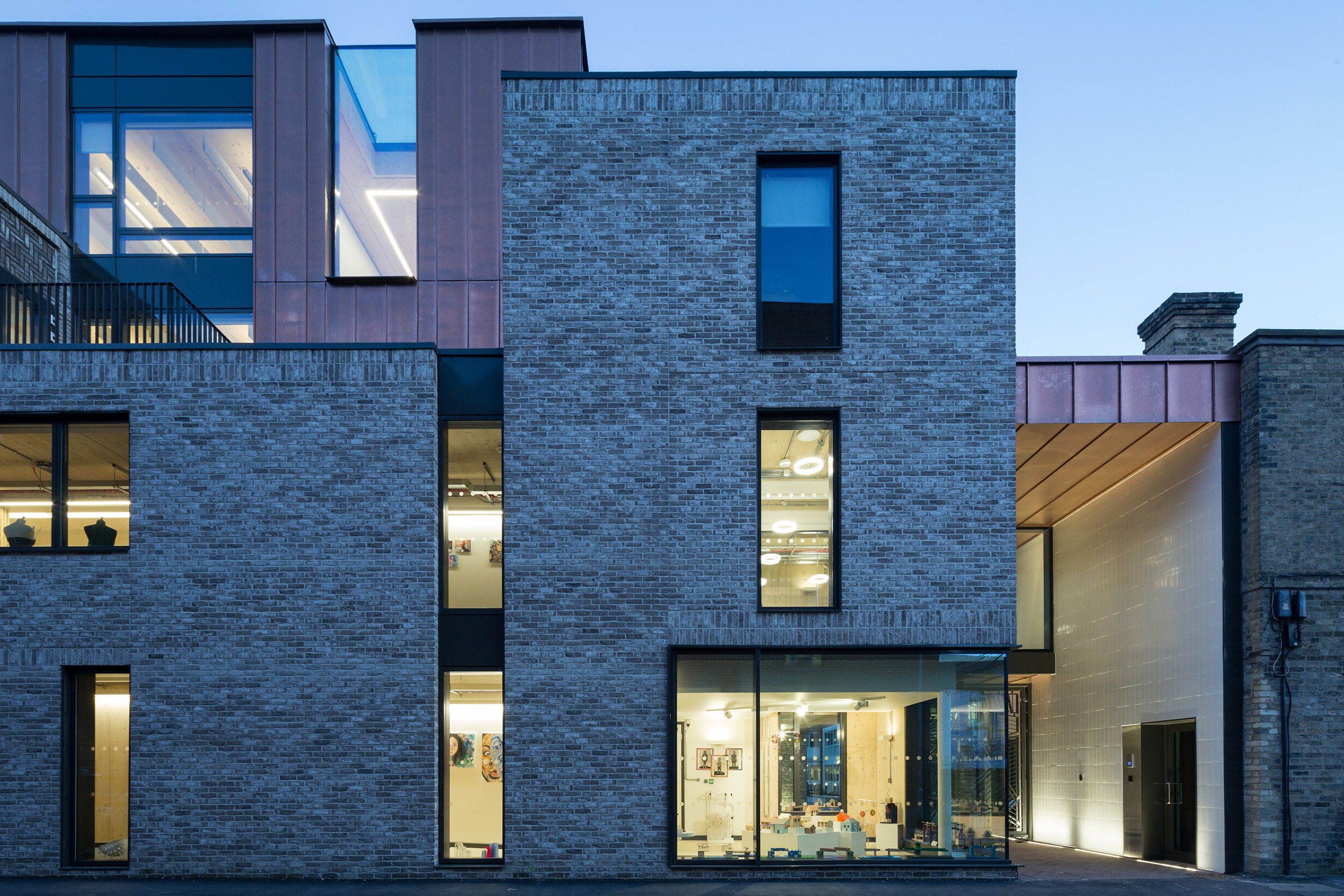 Late evening view of front entrance to cambridge sports learning school by architects CDC studios with lights on